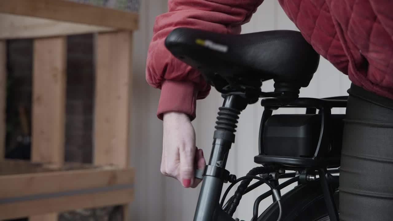 dama ajustando la altura de su nueva bicicleta eléctrica antes de sacarla para el primer viaje