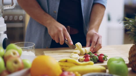 un joven cortando plátanos en la cocina en casa