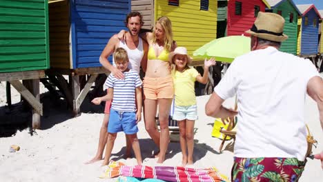 familia de varias generaciones agitando las manos en la playa