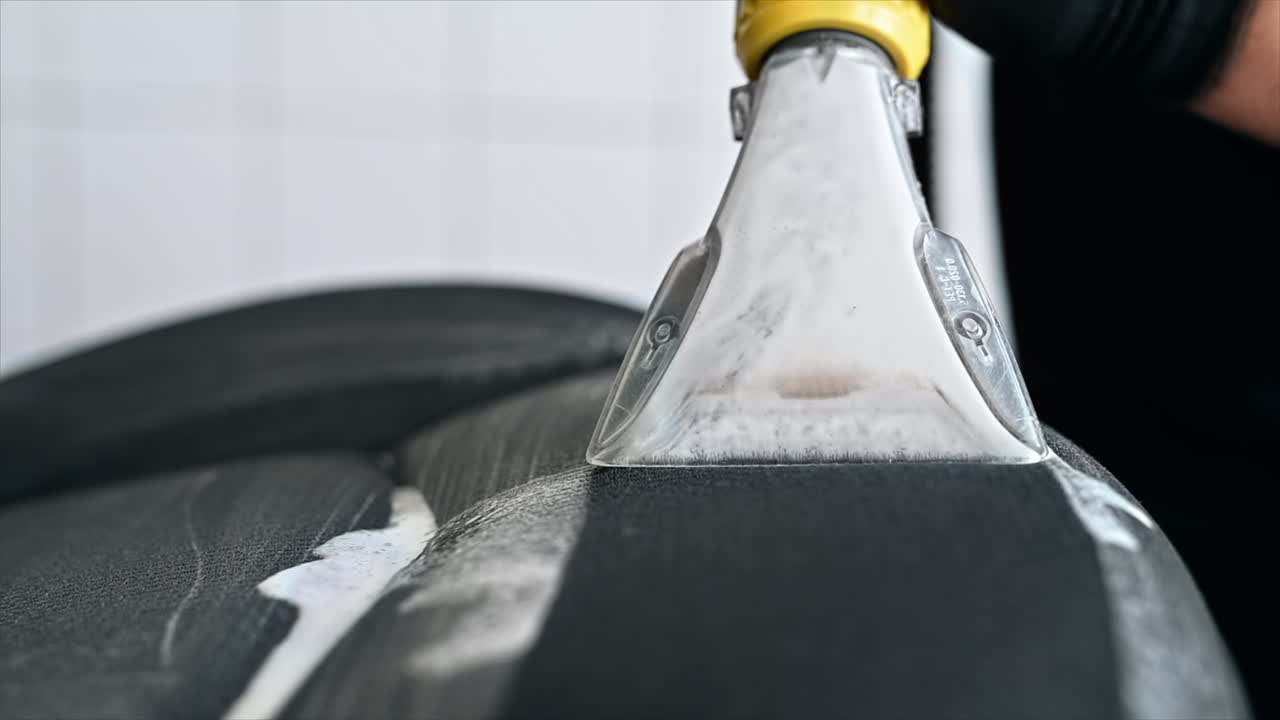 Working cleaner at car wash. Cleaning a seat using a professional vacuum cleaner. Slow motion