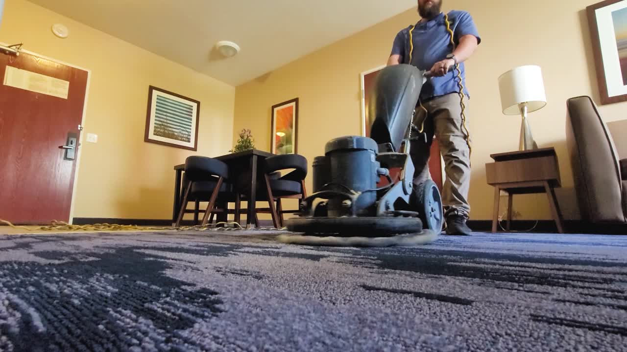 Young male worker cleaning carpet