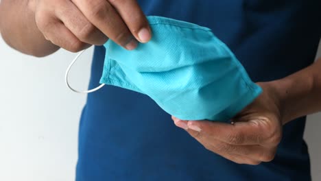 person holding a blue cloth face mask