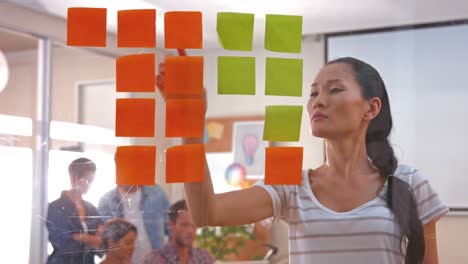 casual businesswoman looking at post it with her colleagues behind