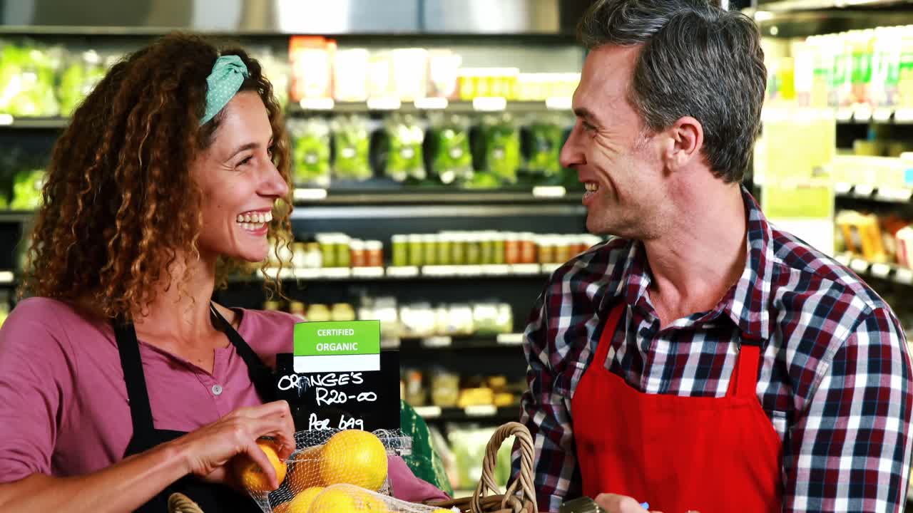 Personal llevando un registro de frutas en un portapapeles en la sección de productos orgánicos