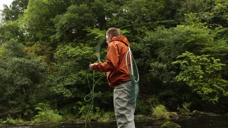 Low-Angle-Aufnahme-Eines-Fliegenfischers,-Der-Versucht,-Einen-Fisch-Im-Fluss-Zu-Fangen