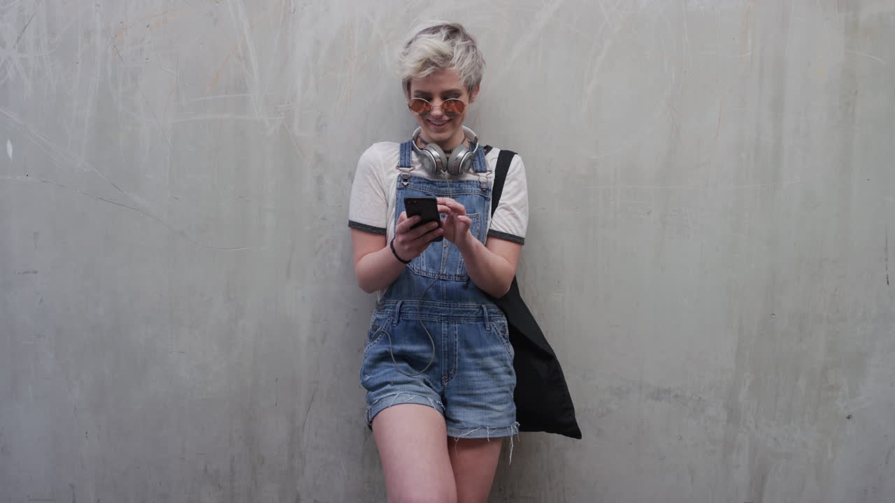 ritratto di una giovane studentessa carina che usa uno smartphone, che invia messaggi di testo, che si gode la navigazione dei messaggi sul cellulare, un'app di comunicazione, rilassata, spensierata, al rallentatore