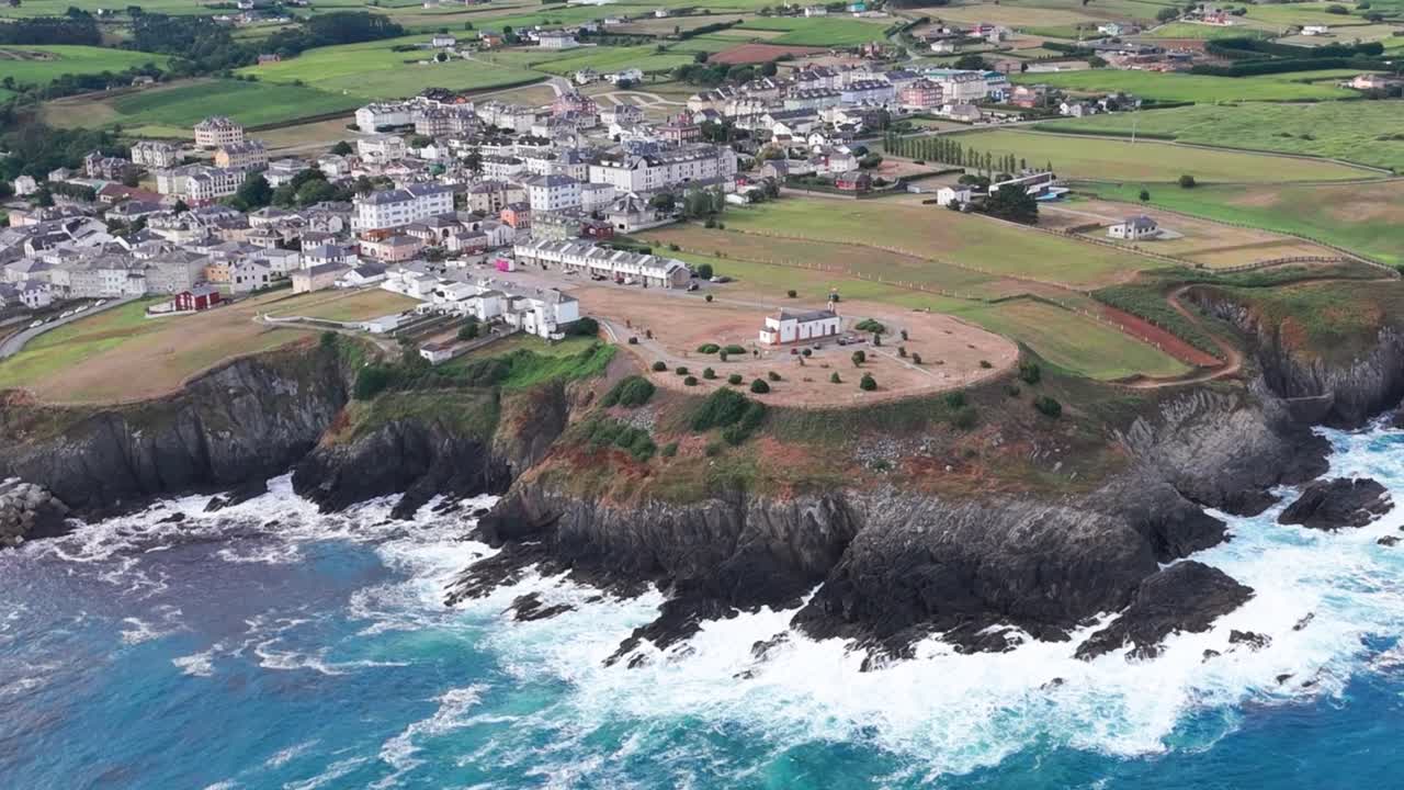 Stunning aerial views capture the Hermitage of La Atalaya, a picturesque Romanic chapel perched above the Cantabrian Sea with a backdrop of the charming town of Navia in Asturias