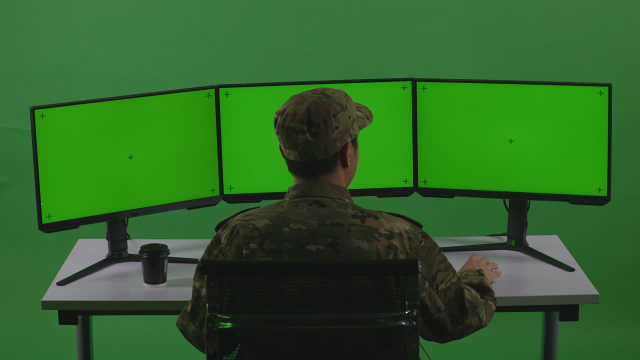 Vista Traseira de Soldado Asiático Feliz Celebrando Enquanto Trabalha com Múltiplos Monitores de Computador (Mockup) em Estúdio de Tela Verde.
