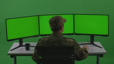 back view of happy asian man soldier celebrating while working with mock up multiple computer monitor in green screen studio