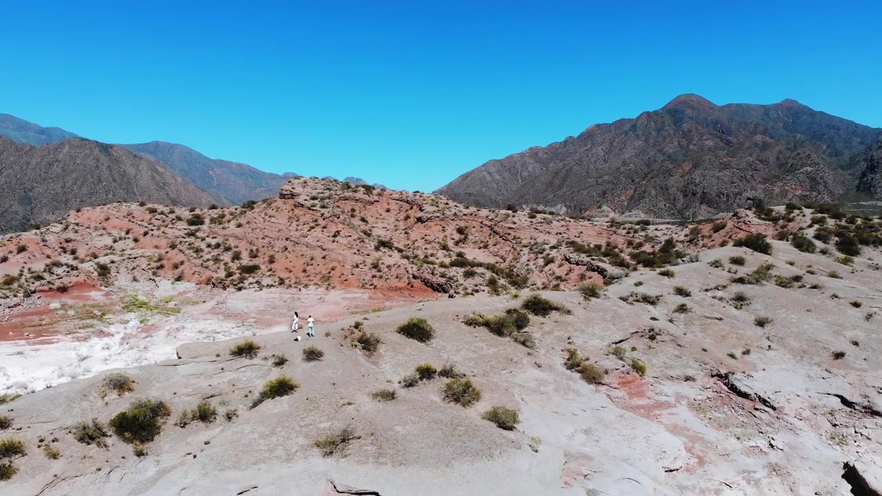 Ripresa aerea panoramica con drone di una coppia che cammina sul bordo di una montagna con lo sfondo della Cordigliera delle Ande