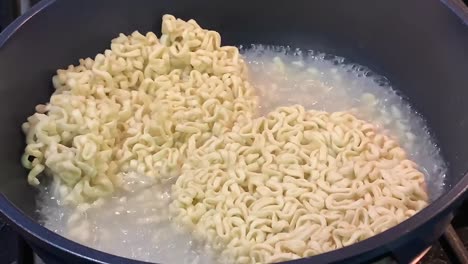 dry instant noodles boiling in a large pot of water