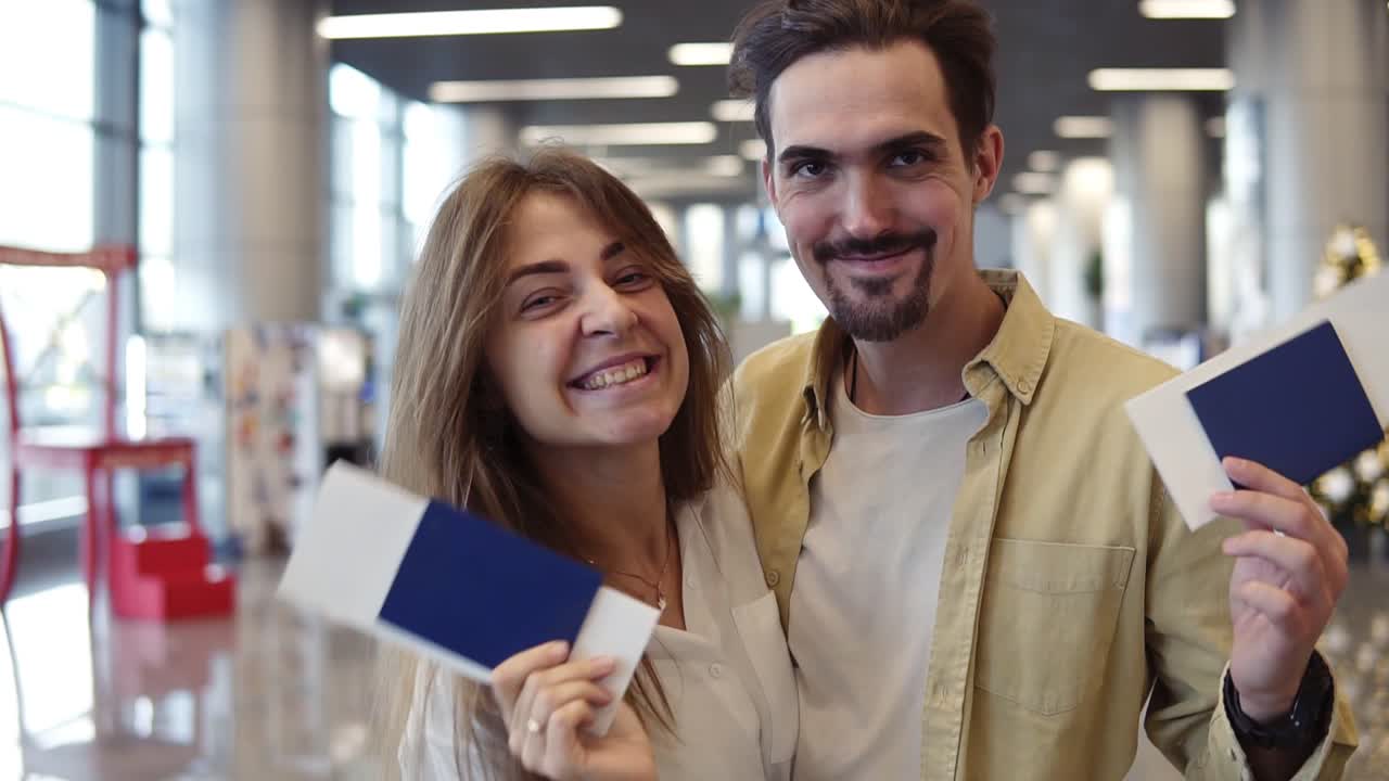 pareja caucásica emocionada yendo de vacaciones y sosteniendo el pasaporte de abordaje en el aeropuerto. agitando con los pasaportes de check-in