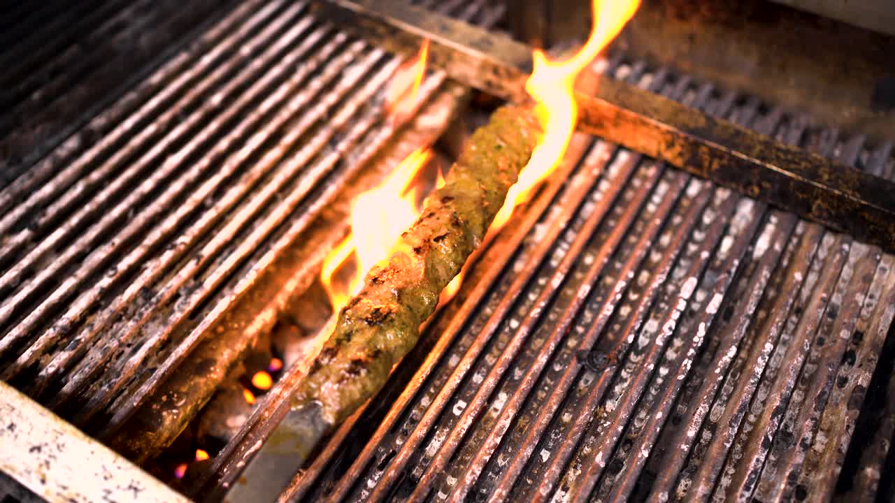 Nice UHD clip of a kebab , meat getting grilled on a nice barbecue. Warm tones with some nice flame action.