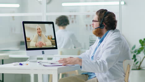 male doctor giving online consultation to elderly woman