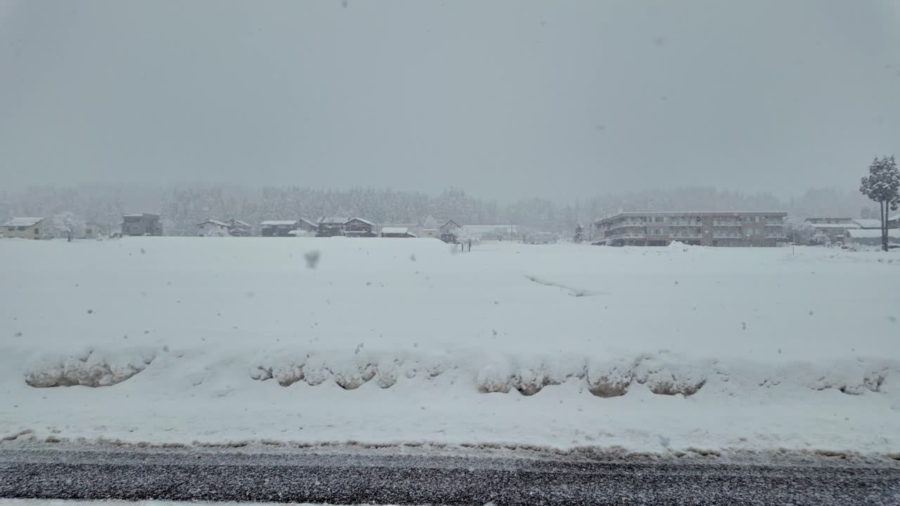 Peaceful winter scene with snow blanketing houses and open fields