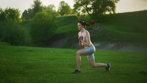 una joven y hermosa mujer salta cambiando sus piernas en el parque al atardecer.