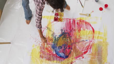 video de una artista femenina biracial pintando en el suelo en un estudio