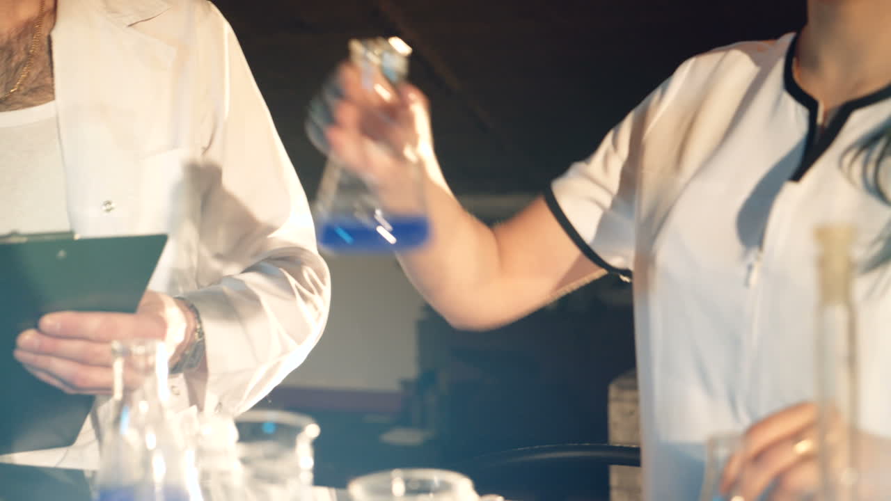 two doctors in eyglasses are experimenting with test tubes with chemicals at a table in the laboratory on a black background. Experiments in the laboratory