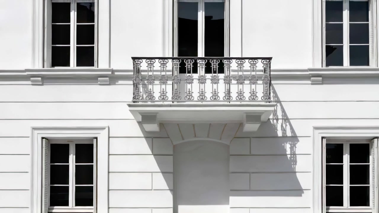 Telecamera che si allontana rivelando un balcone centrale con doppie porte sulla facciata stradale, con l'ombra della ringhiera.
