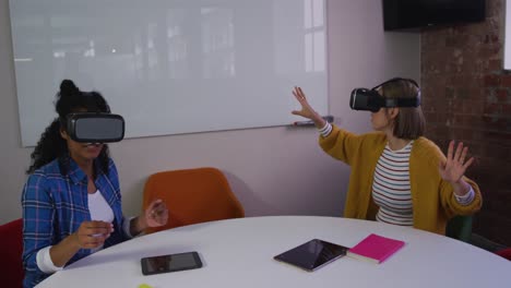 diversas compañeras de negocios sentadas en la mesa usando auriculares vr en la sala de reuniones