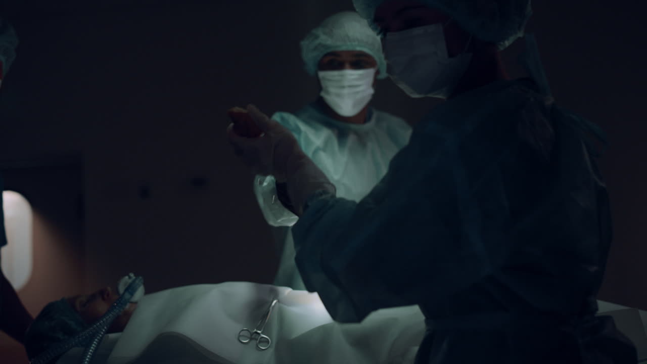 Professional surgeon begin surgical operation in dark hospital emergency room.