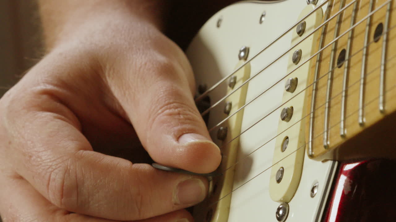 Close Up on Pickups of Stratocaster Guitar As Guitarist Plucks Strings with Plectrum and Twangs on Higher Chord Notes 4K