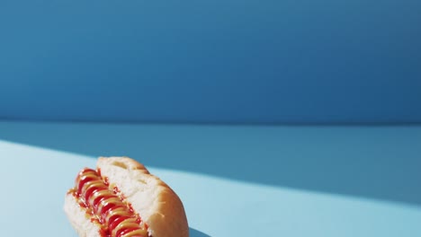 video of hot dog with mustard and ketchup on a blue surface