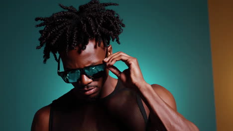 stylish black man with dreadlocks adjusting sunglasses