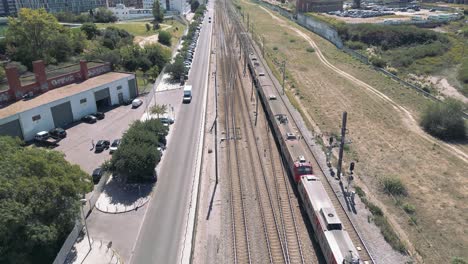 suburban passenger train moving in a railway next to a road in urban area, lisbon