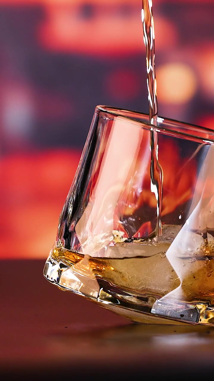 Whisky versato in un bicchiere con ghiaccio