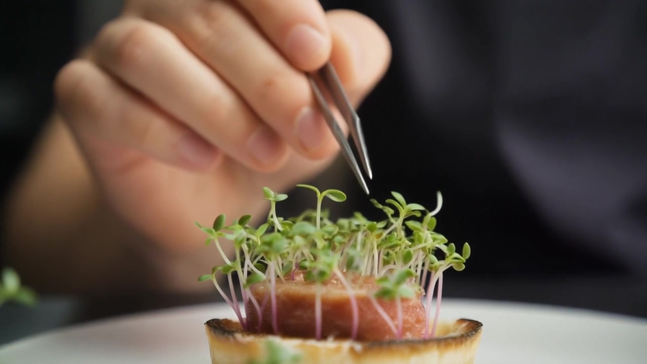 Chef che impiattano un antipasto gourmet con micro-ortaggi usando le pinzette
