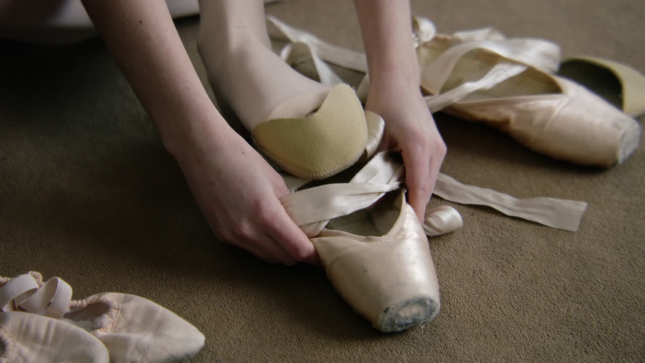una bailarina atando zapatos de punta