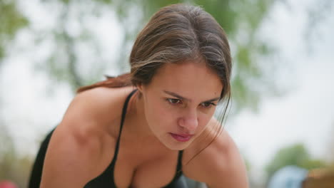 close-up portrait of focused woman preparing for sprint, intense concentration, outdoor workout, fitness training, athletic energy, determined to take off, sport motivation, strong mindset