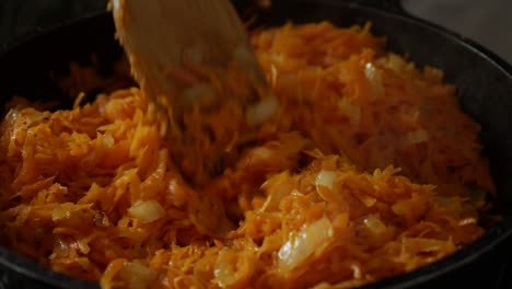 freír cebollas y zanahorias ralladas en una sartén con aceite. revolver freír en una bandeja con una espátula de madera