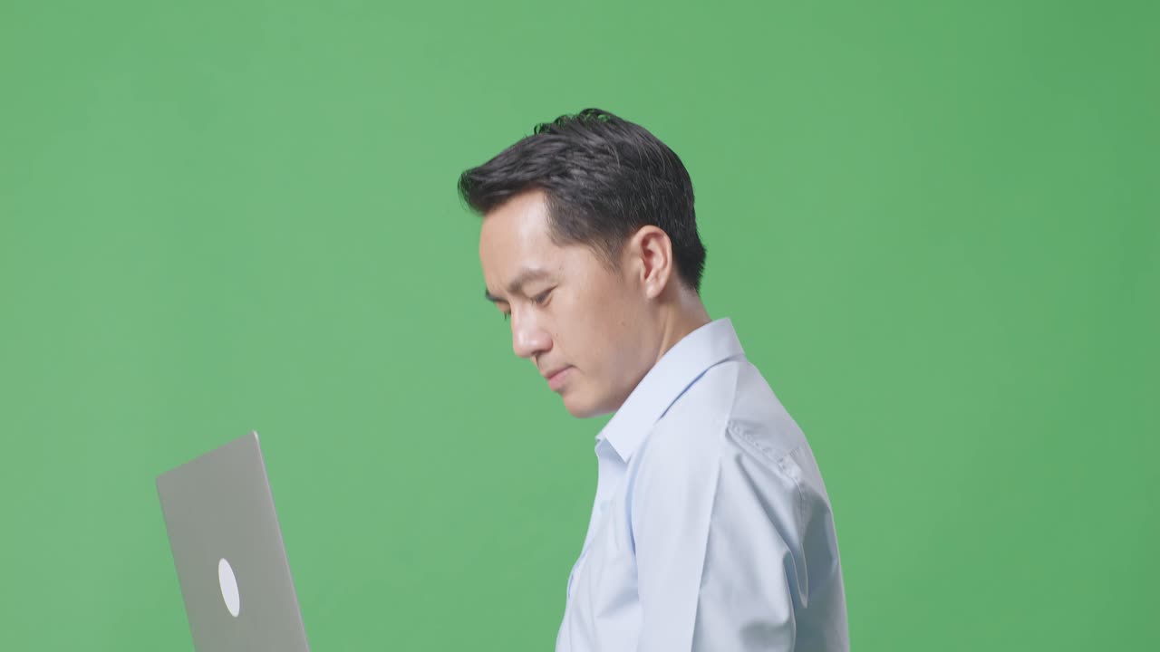 스튜디오에서 녹색 화면 배경에서 는 동안 노트북 컴퓨터를 사용하는 아시아 사업가의 측면 뷰 클로즈업