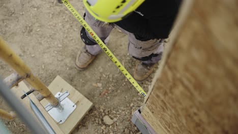 trabajador de cuello azul que mide la distancia con cinta métrica en el sitio de construcción