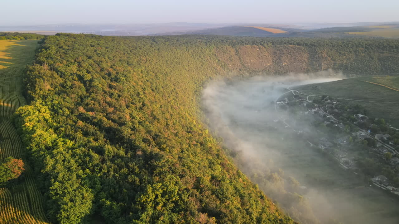 Aerial drone view of the Old Orhei at sunset. Valley with river and fog, village, hills in Moldova