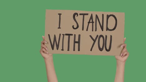 female hands hold a poster from a cardboard box with the words i stand with you. protest against racism and police brutality. isolated a green screen, chroma key. close up. slow motion