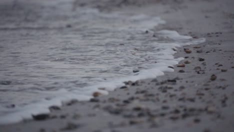 Zeitlupe,-Meeresflut,-Die-über-Strand-Voller-Muscheln-Und-Kleiner-Felsen-An-Land-Spült