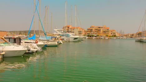 calm marina in cap d’agde with yachts and colorful buildings under blue summer sky