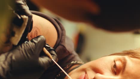 young woman getting hand-poked arm tattoo in studio