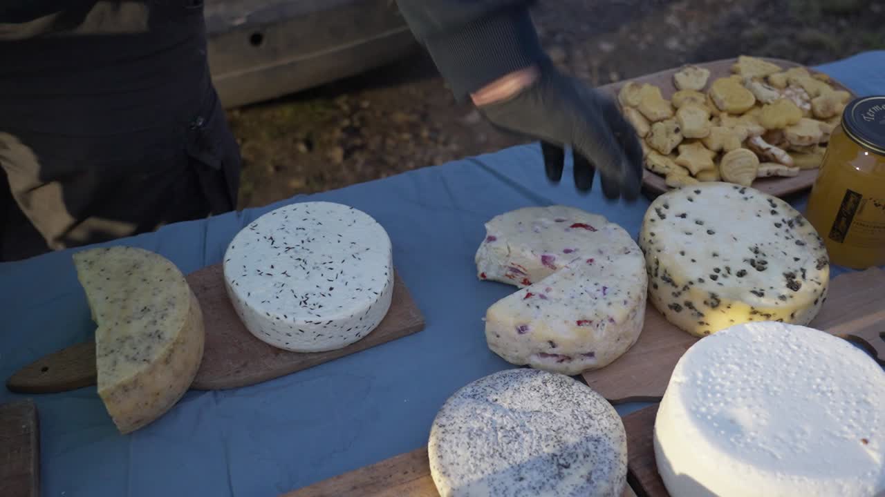 야외 시장 의 나무 테이블 에 전시 된 여러 가지 공예 치즈