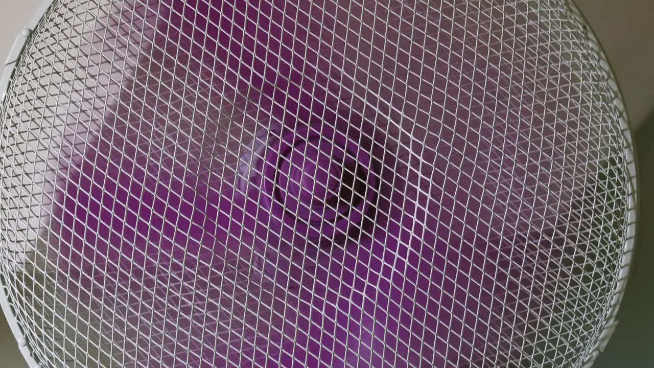 electrodomésticos ventilador eléctrico hojas de plástico púrpura giratorias que circulan el aire en la habitación de cerca