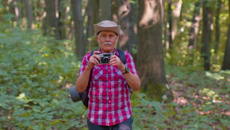 Abuelo-Anciano-En-Viaje-De-Senderismo-Explorando-La-Vida-Silvestre-Tomando-Fotos-En-El-Bosque-Con-Cámara-Retro