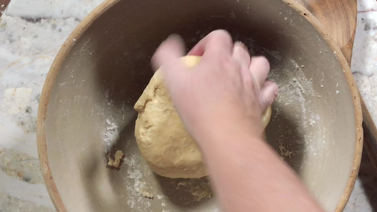 overhead view of hands kneading dough into a dough ball