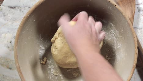 overhead view of hands kneading dough into a dough ball