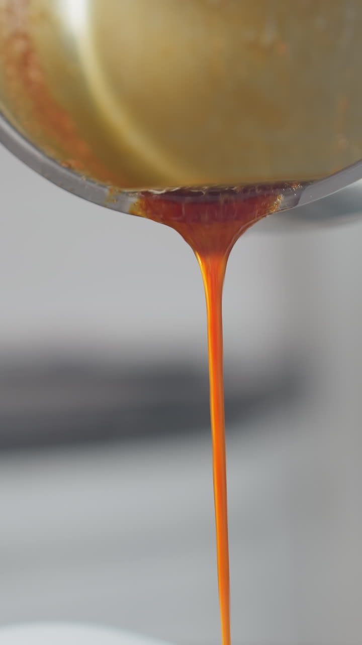Close-up of person pouring vibrant red soup from metal pot while stirring in white bowl, rich liquid flows smoothly, blending with ingredients as hands carefully mix
