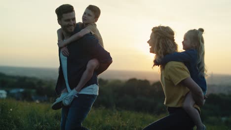 parents with kids walking at the meadow in summer day.