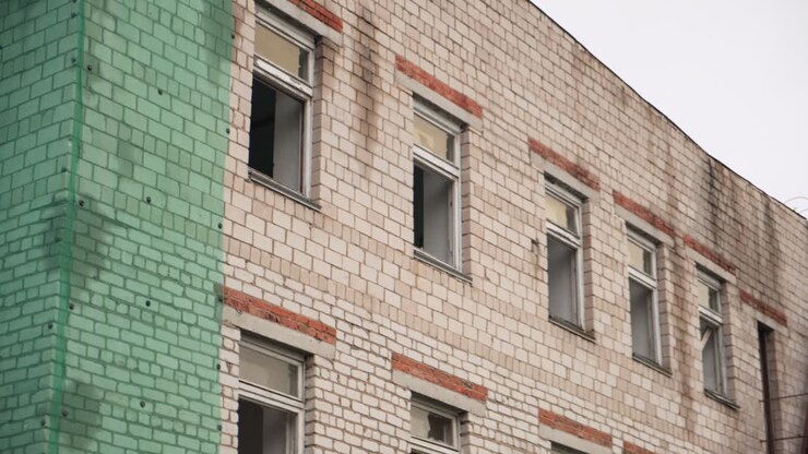 Edificio in mattoni abbandonato con finestre rotte e scala antincendio