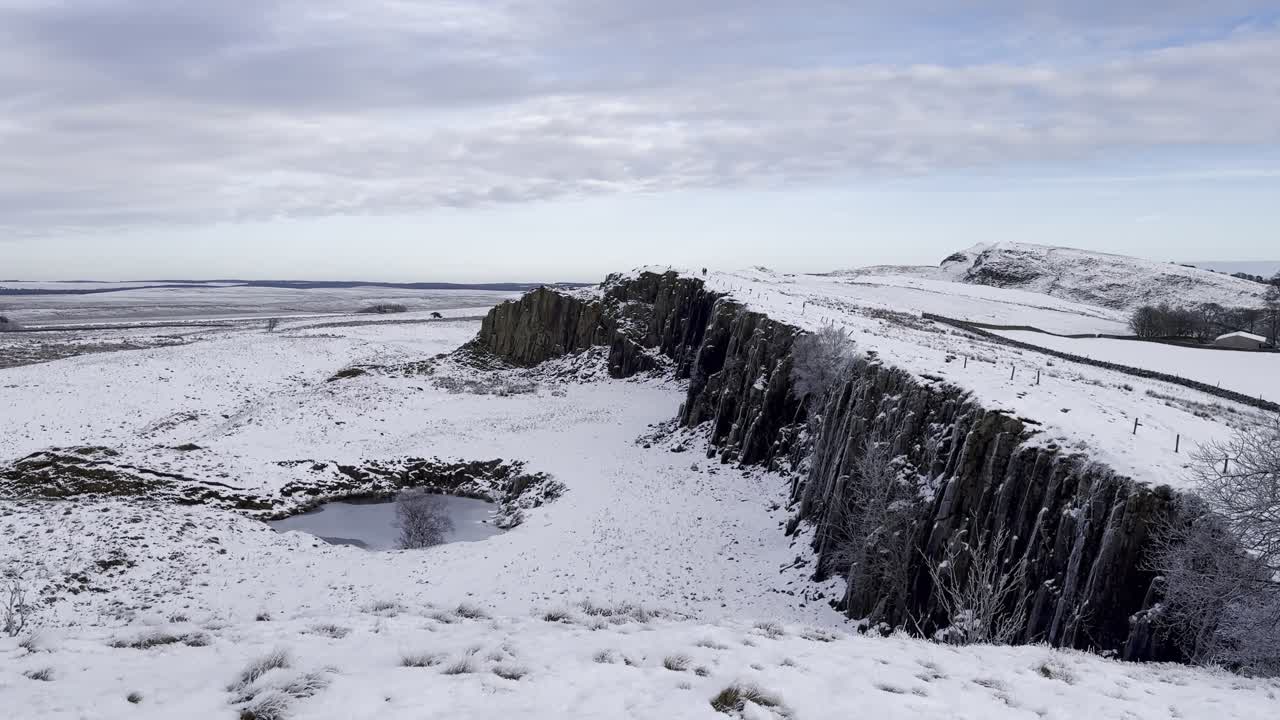 Snow-covered landscape by Hadrian’s Wall near Steel Rigg in Northumberland, England. Containing dramatic Whin Sill ridge and frozen moorland on UNESCO World Heritage Site along Roman Wall